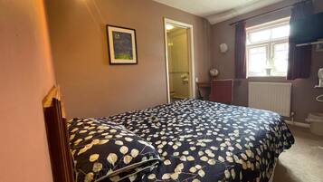 Un dormitorio con una cama, un cuadro en la pared y una ventana con cortinas.