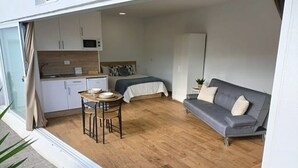 A compact living space with a kitchenette, a bed, a sofa, and a dining area. - Estudio Nuevo con Jardín Privado en Pleno Valle (La Laguna)