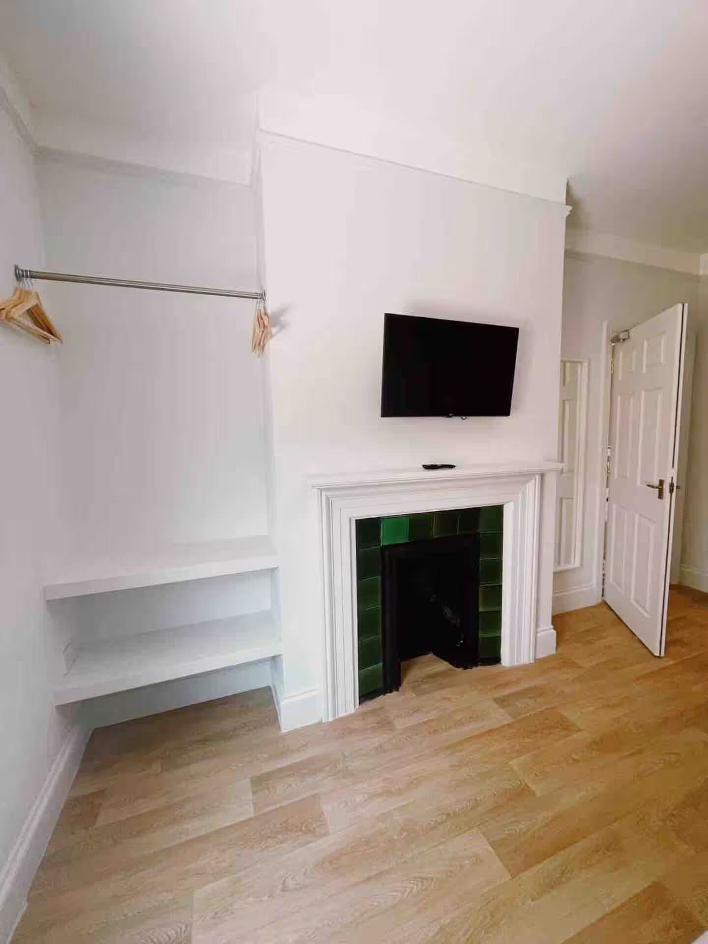 A room with a fireplace, a mounted television, and a wooden floor.