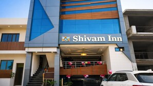 A modern hotel named Shivam Inn with a prominent blue and brown facade, a visible entrance with a staircase, and a car parked in front. - Hotel Shivam Inn Agra (Agra)