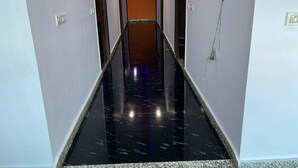A hallway with a black marble floor, white walls, and a wooden door at the end. - Hotel Shivam Inn Agra (Agra)