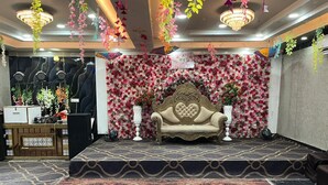 A stage with a floral backdrop and a sofa, surrounded by a patterned carpet and hanging decorations. - Hotel Shivam Inn Agra (Agra)