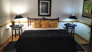 Een slaapkamer met een bed, twee nachtkastjes, een potplant en een lijst aan de muur.