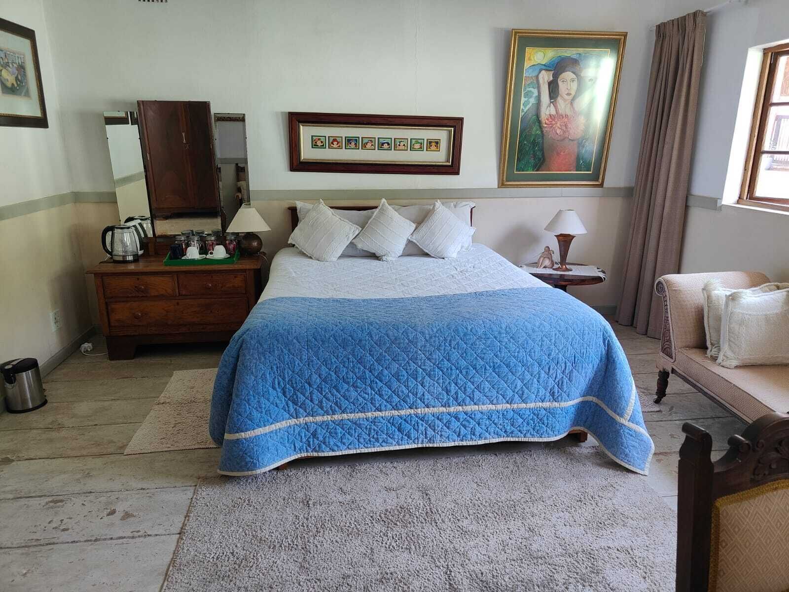 A bedroom with a bed, a dresser, a nightstand, a painting, and a window with curtains.