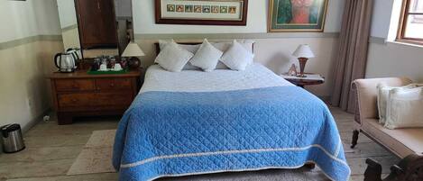 Quarto com cama, cómoda, mesa de cabeceira, quadro e janela com cortinas.