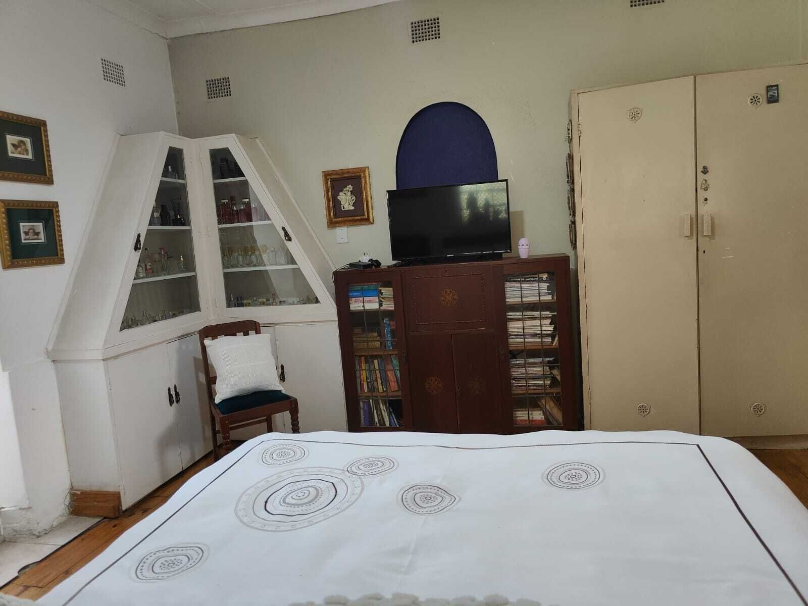 A bedroom with a bed, a window, a television, a wardrobe, and a chair.