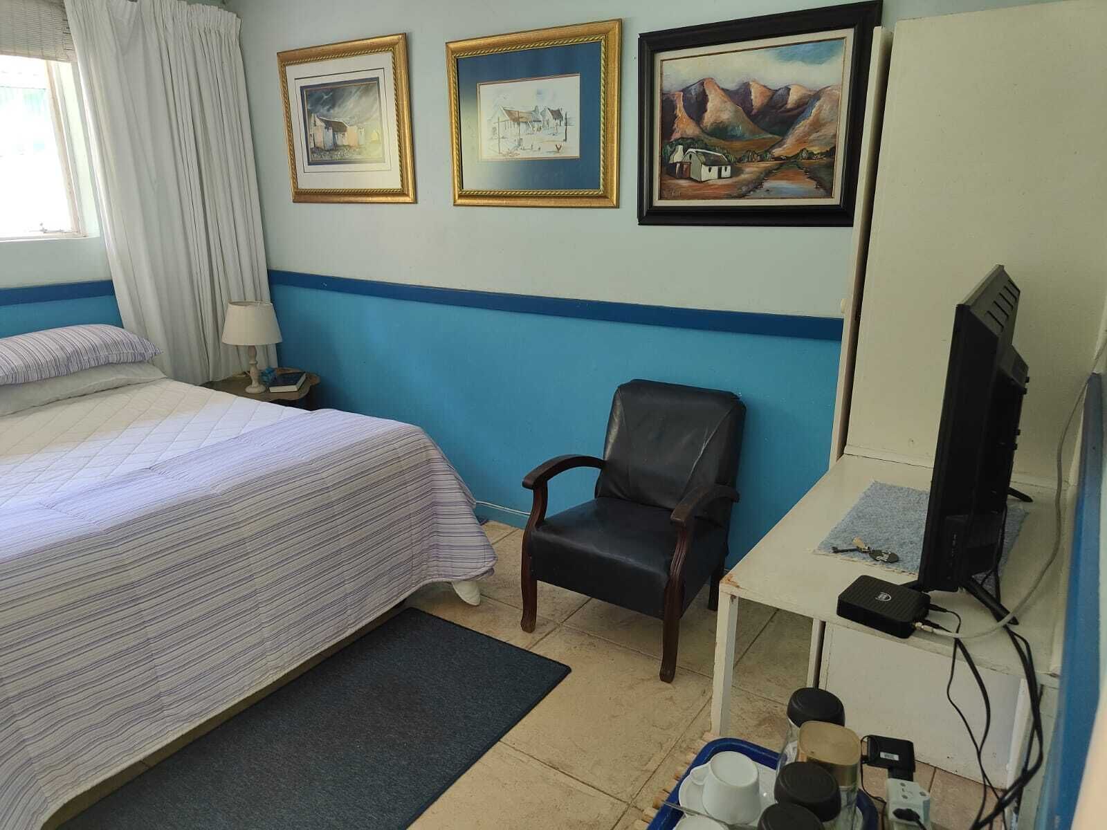 Una habitación de hotel con una cama, un escritorio con una computadora y tres cuadros en la pared.