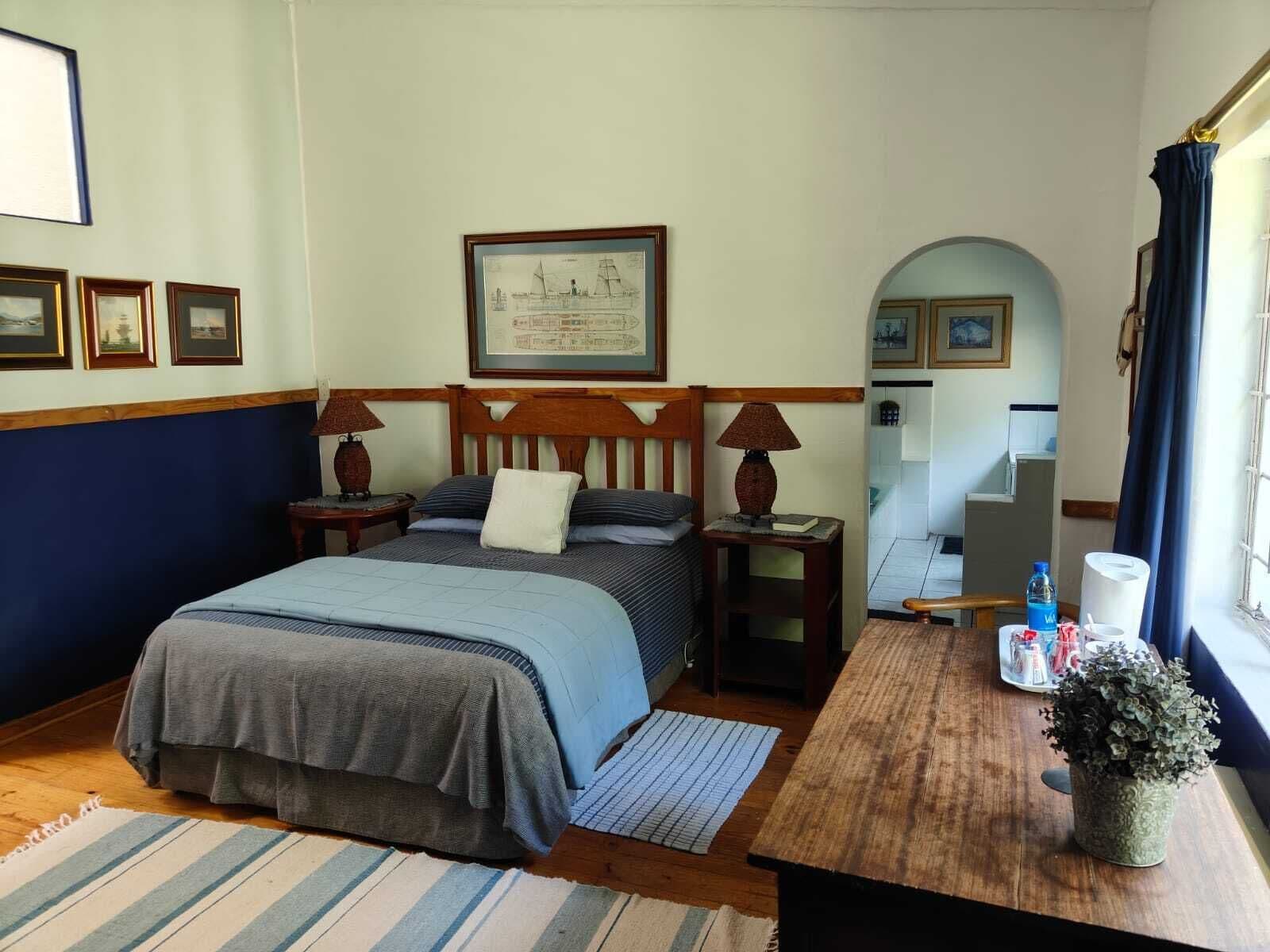 Une chambre à coucher bien rangée, avec un lit, des tables de chevet, une carte encadrée accrochée au mur et une fenêtre avec des rideaux.