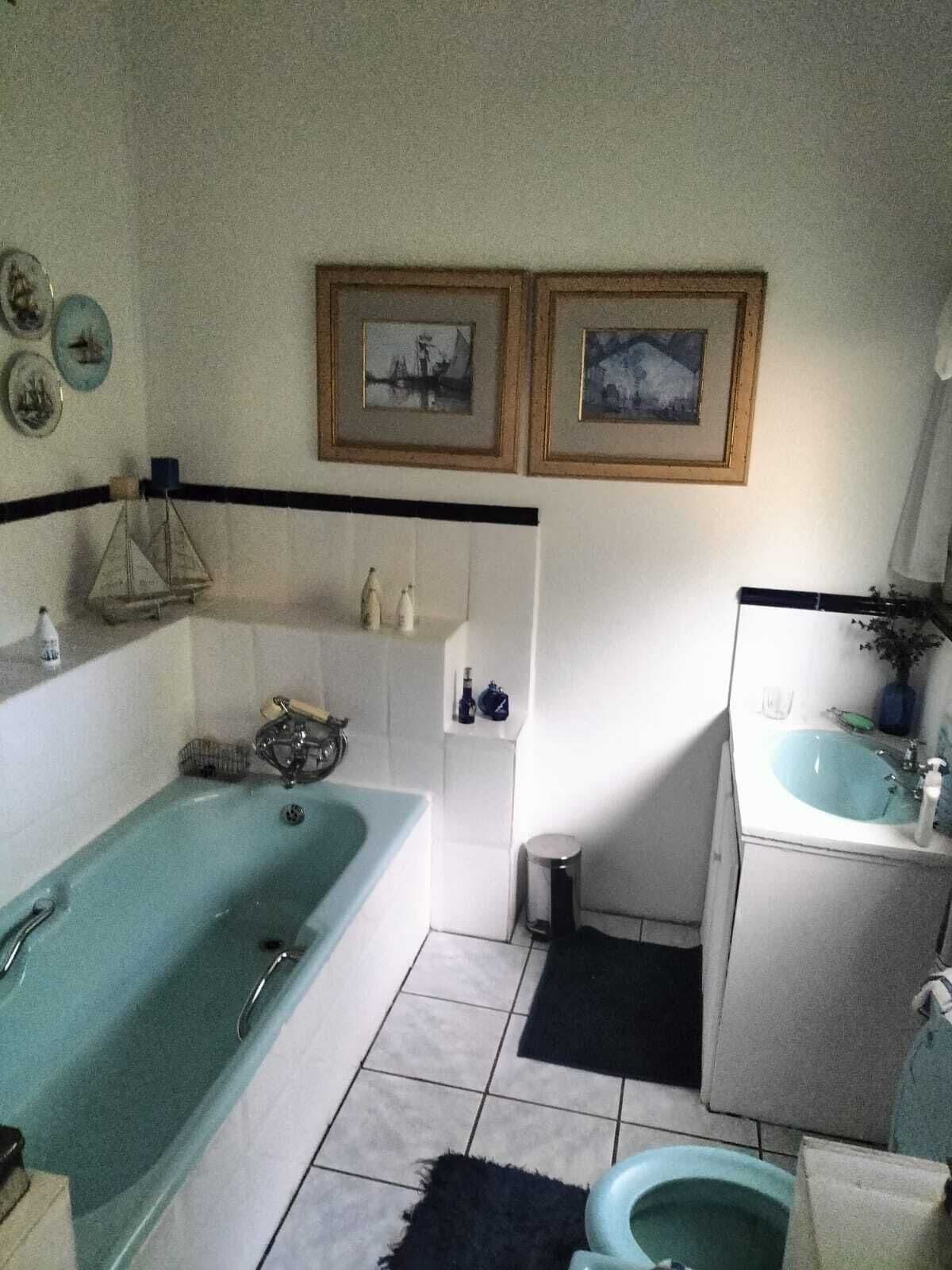 A bathroom with a bathtub, toilet, sink, and two framed pictures on the wall.