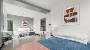 Una habitación de hotel moderna con una cama grande, un escritorio y una silla. Hay una ventana que deja entrar luz natural y ofrece vistas al exterior.