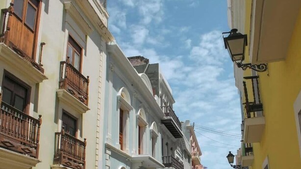 Una calle estrecha con edificios que tienen balcones y un farol.