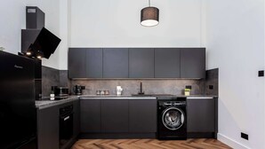 Une cuisine moderne avec des meubles de rangement aux couleurs sombres, un lave-vaisselle encastré et un parquet en bois disposé en chevrons.