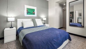 A modern hotel room with a large bed, two bedside tables, a wall-mounted mirror, and a framed picture above the bed. - Near La Placita | Free Breakfast | TV With Netflix (San Juan)