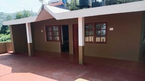 A building with a flat roof, multiple windows, and a visible water tank on the roof. - Hotel Shree Homestay (Ootacamund)