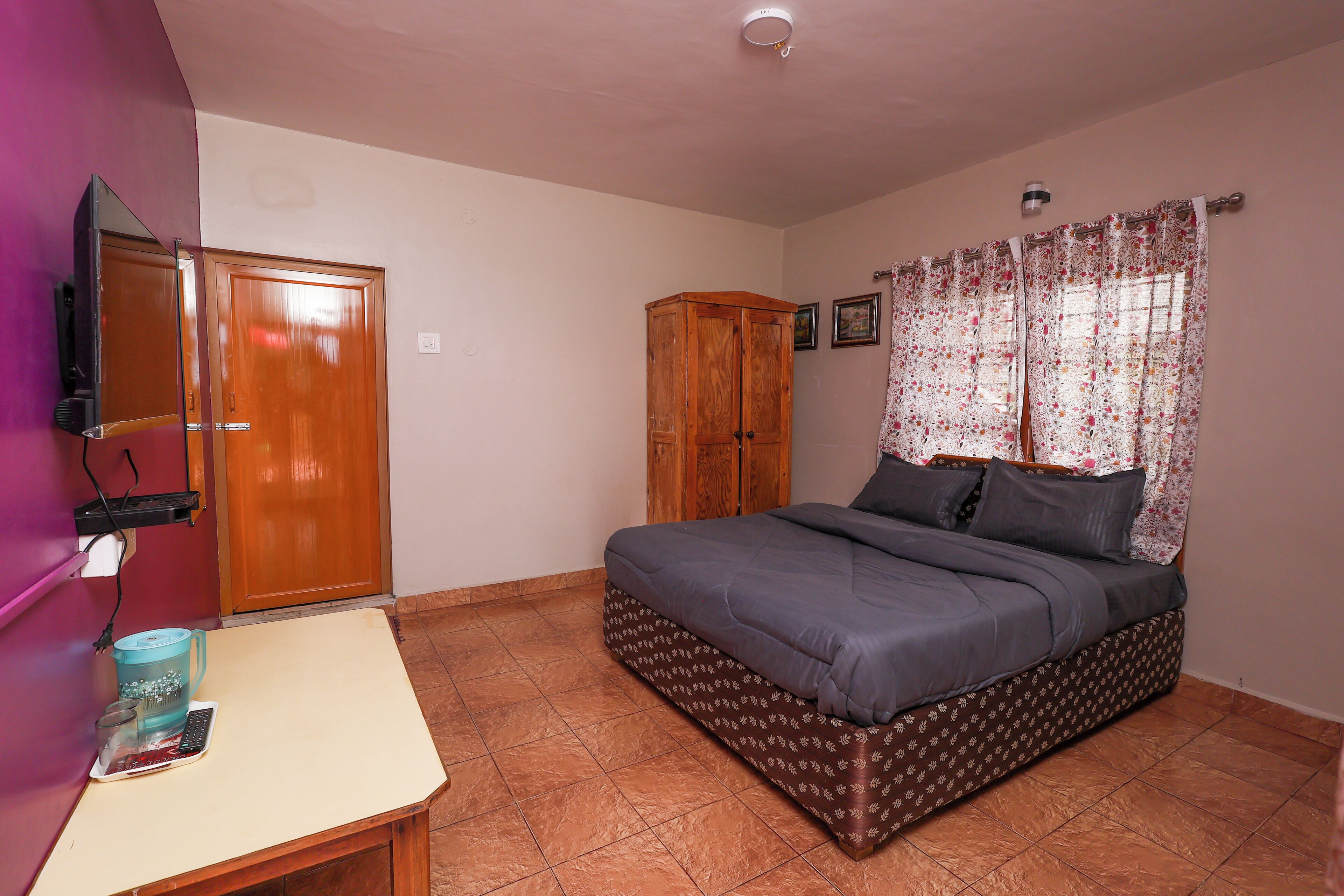 A bedroom with a bed, a wardrobe, a desk with a computer, and a television.