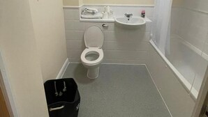 Et lille, kompakt badeværelse med toilet, vask og bruser.