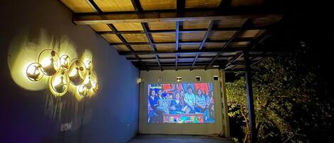 A projection screen displaying a colorful image, a ceiling with wooden beams, and wall-mounted lights.