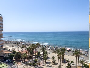 Une plage bordée de palmiers, avec des parasols et un ciel bleu azur.