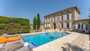 A pool area with lounge chairs and a stone building in the background. - Property XVIII of 500 m2 with private pool and park 20 minutes from Bordeaux. (Virsac)