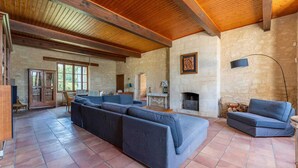 A spacious living room with a large sectional sofa, a fireplace, and a stone wall. - Property XVIII of 500 m2 with private pool and park 20 minutes from Bordeaux. (Virsac)