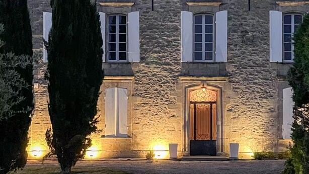 A stone building with a central entrance, flanked by windows with shutters, and illuminated by ground lights. - Property XVIII of 500 m2 with private pool and park 20 minutes from Bordeaux. (Virsac)