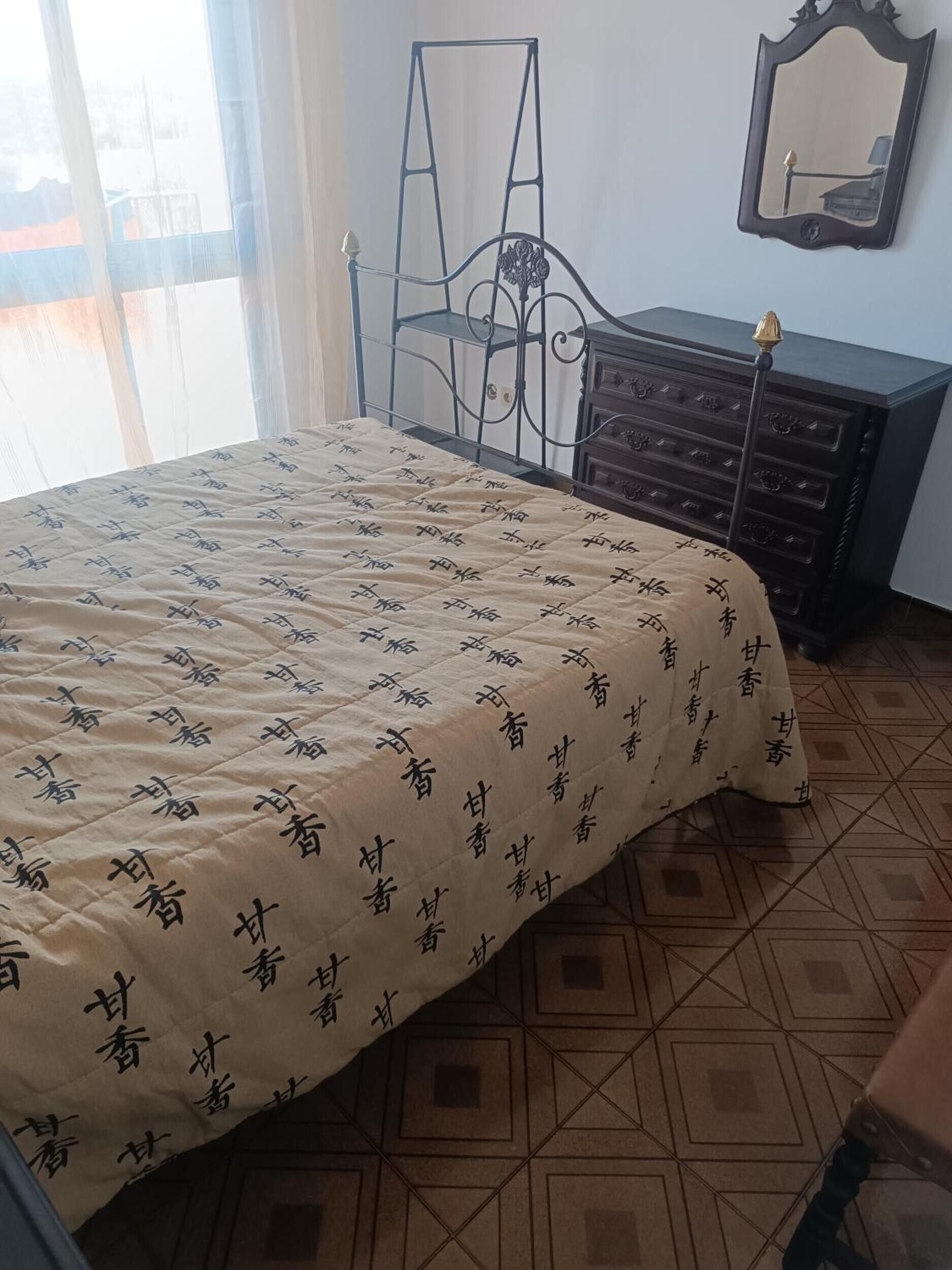 A bedroom with a bed, a dresser, a chair, and a mirror.
