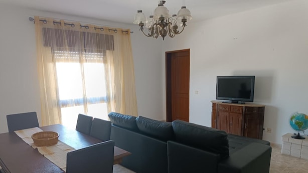 Ein Wohnzimmer mit einer Couch, einem Esstisch, Stühlen, einem Fernseher und einem Globus.