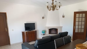 Ein Wohnzimmer mit einer Couch, einem Fernseher, einem Kamin und einem Esstisch.