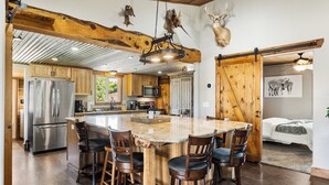 Une cuisine spacieuse dotée d’un îlot central, de tabourets de bar en bois et d’un grand réfrigérateur.