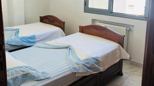 Une petite chambre propre, avec deux lits en bois, une fenêtre donnant sur un beau paysage et un radiateur.