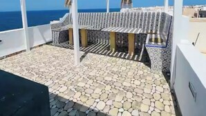 A rooftop terrace with a white pergola, stone flooring, and a view of the sea. - Dar sfar with sea view (Mahdia)