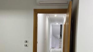 A hallway with a tiled floor, a wooden door, and a ceiling-mounted air conditioning unit. - Dar sfar with sea view (Mahdia)