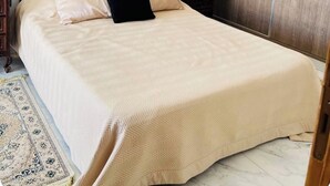 A neatly made bed with a wooden headboard, a bedside table, and a wardrobe. - Dar sfar with sea view (Mahdia)