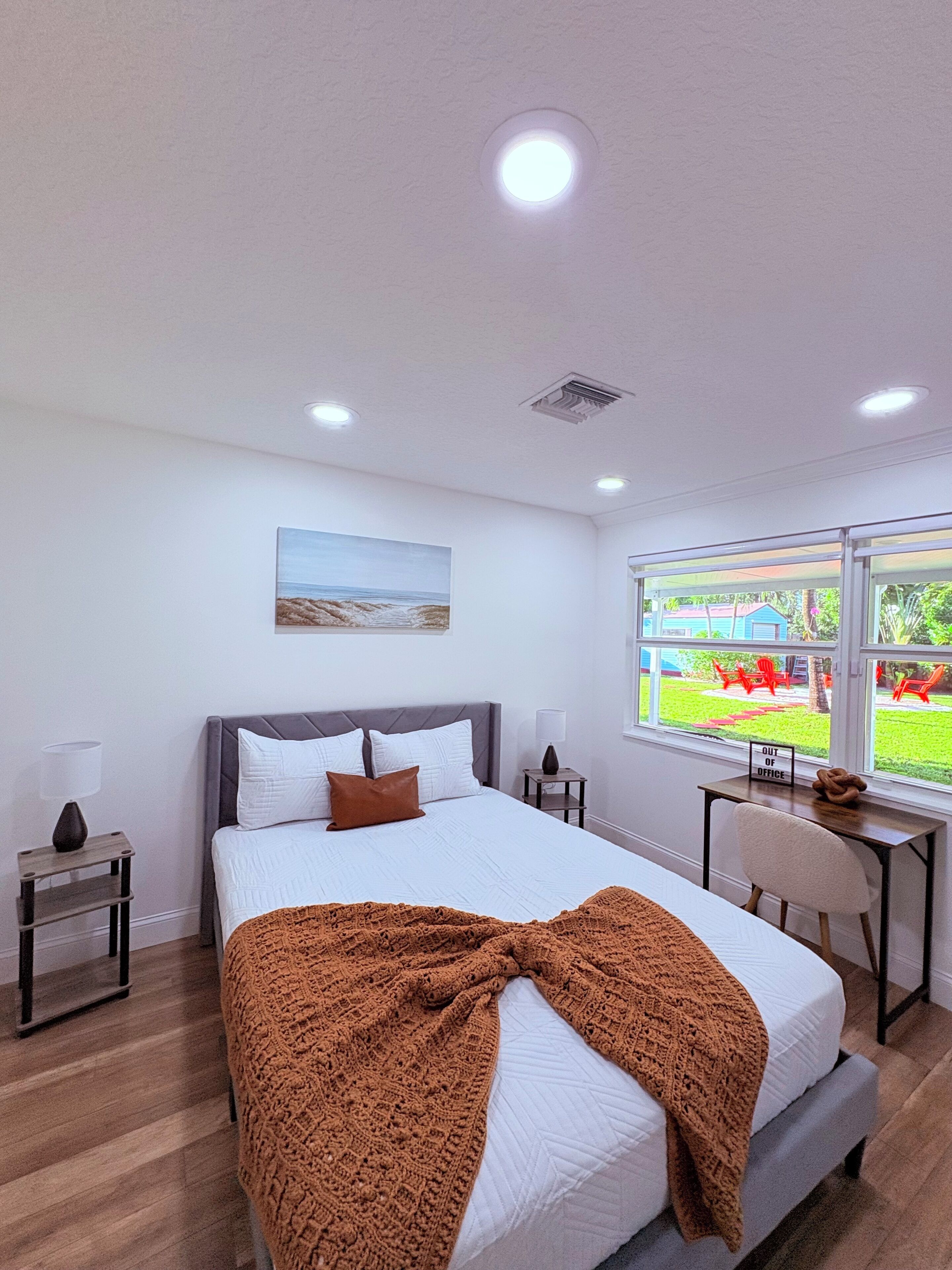 Une chambre à coucher avec un lit, une fenêtre donnant sur un jardin et un tableau accroché au mur.