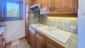 A compact kitchen with wooden cabinets, a window, and a tiled backsplash.