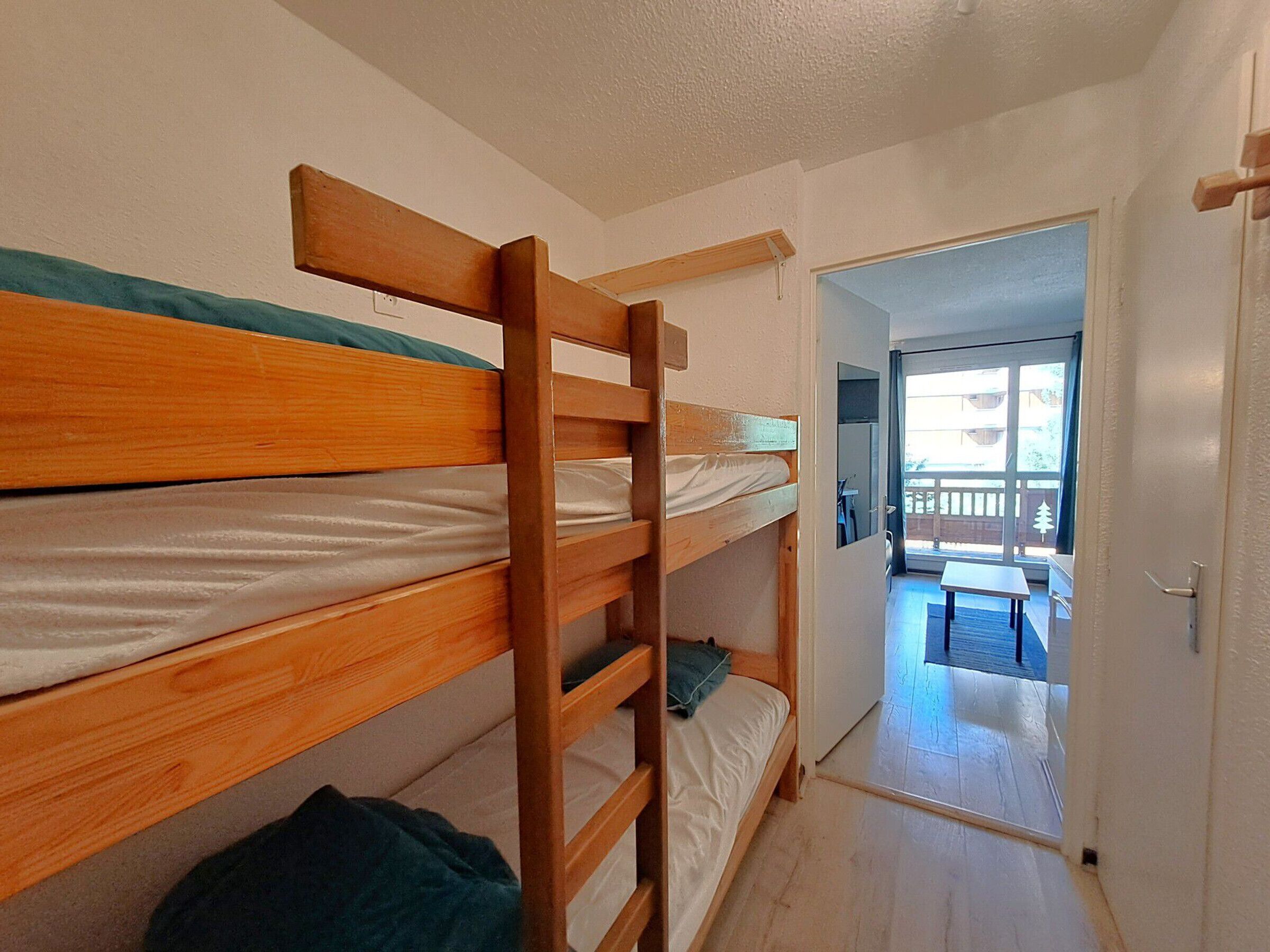 Una habitación con literas, una puerta que da a un balcón y vistas al exterior.
