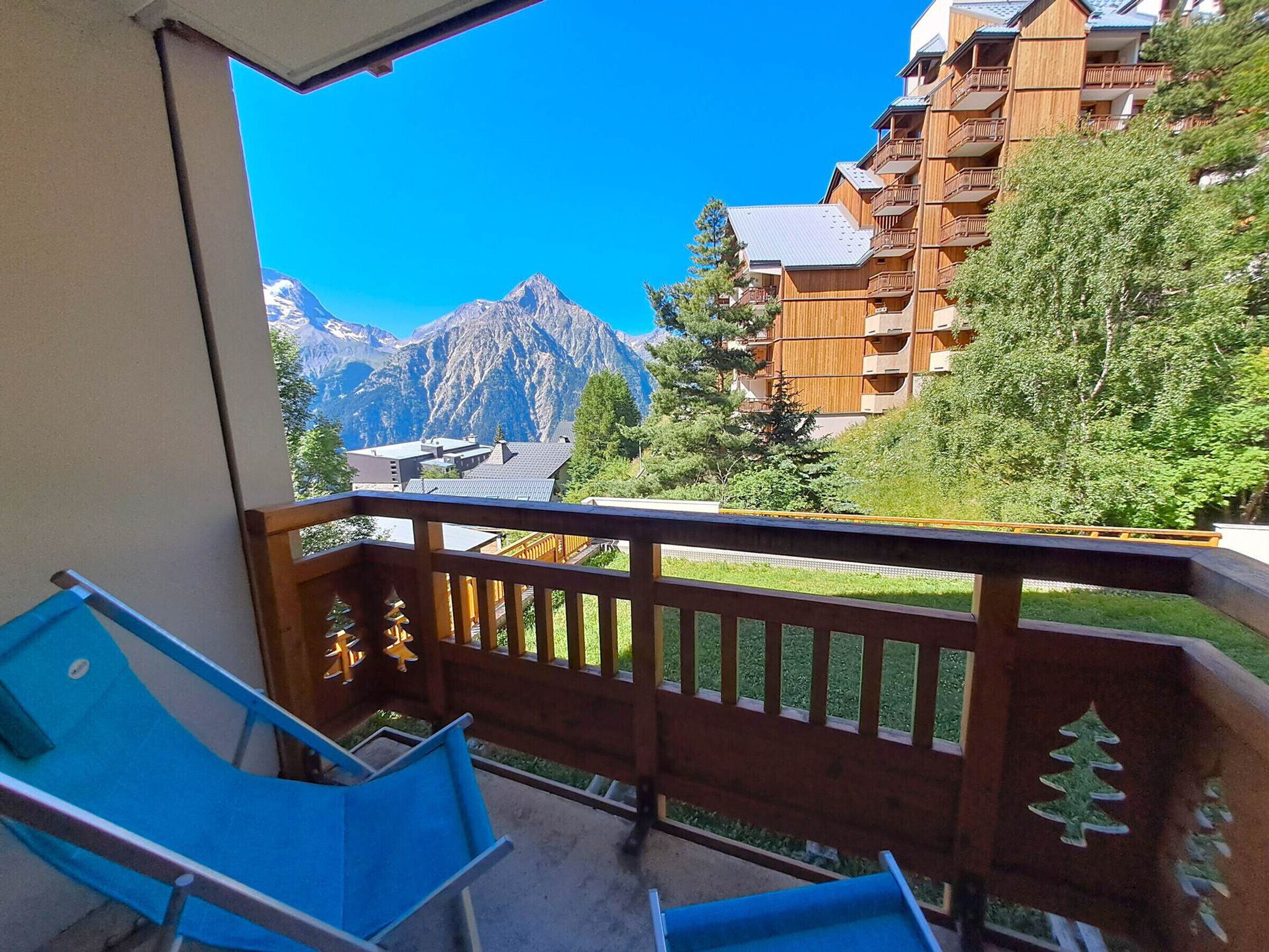 A balcony with a view of mountains and a wooden building.