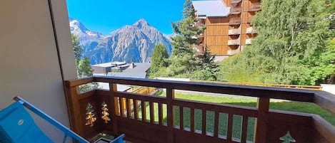 A balcony with a view of mountains and a wooden building.