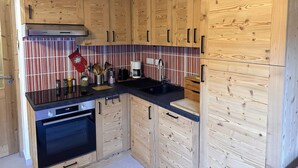 A kitchen with wooden cabinets, a Bosch oven, a striped backsplash, and a coffee maker.