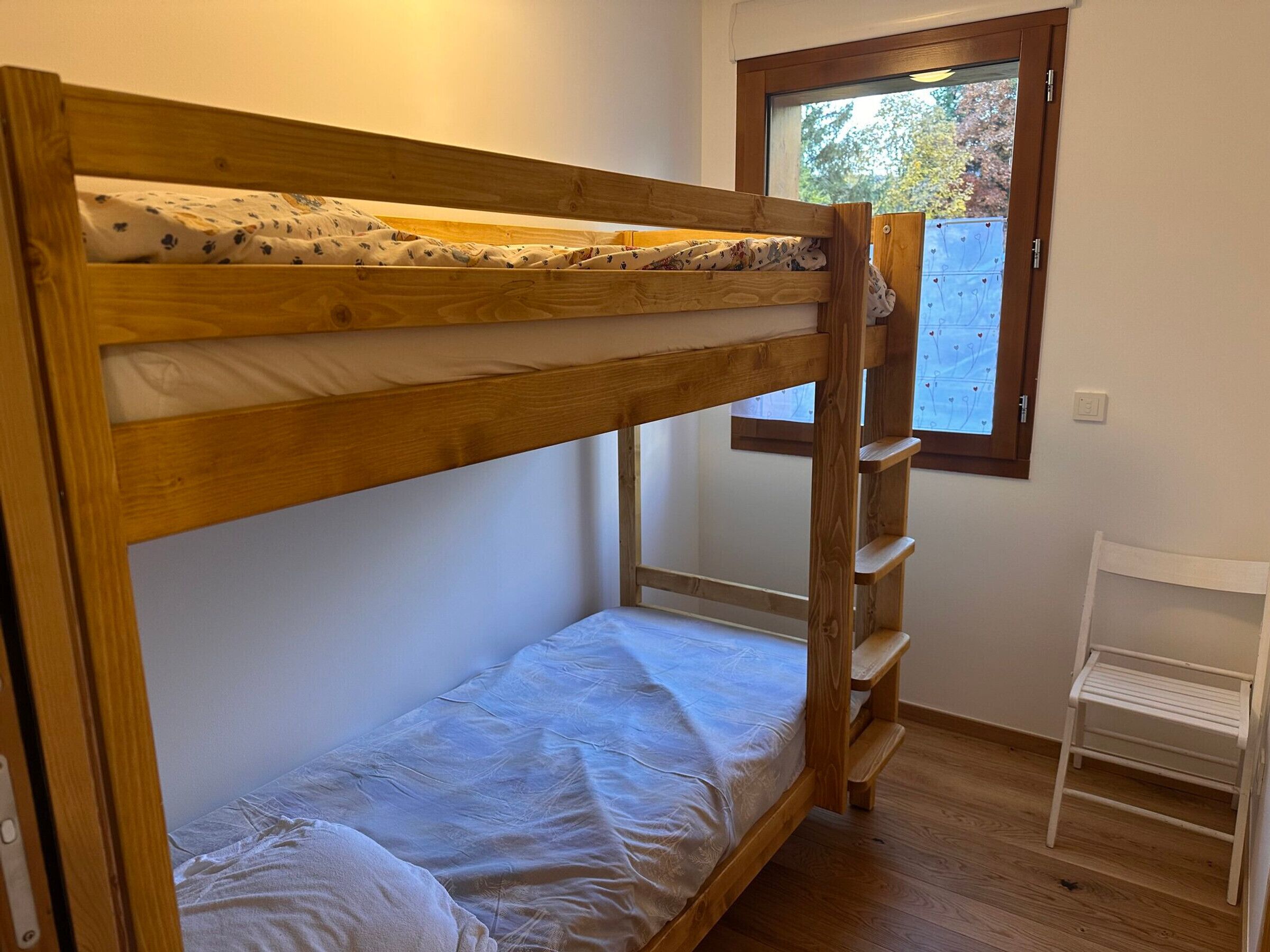 Una litera con estructura de madera y un pequeño estante blanco.