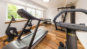 Un gimnasio con cintas de correr, mancuernas y una banca de pesas.
