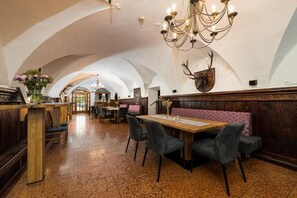 A restaurant with a high arched ceiling, wooden tables, and booths. - Hotel Bräurup  (Mittersill)