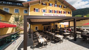 Un restaurante con terraza, fachada amarilla y un letrero que dice "Brauerei Gasthof Bräuerei".