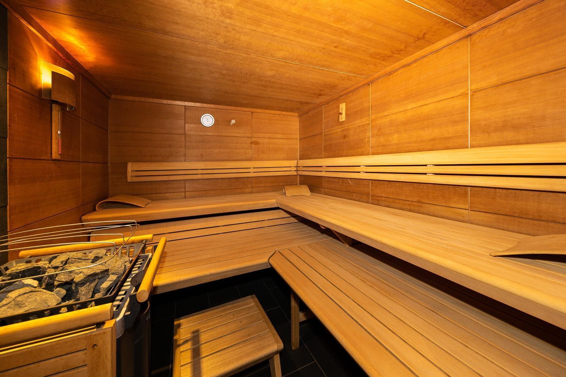 Eine Sauna mit Holzbänken und einem Steinelement zur Wärmequelle.