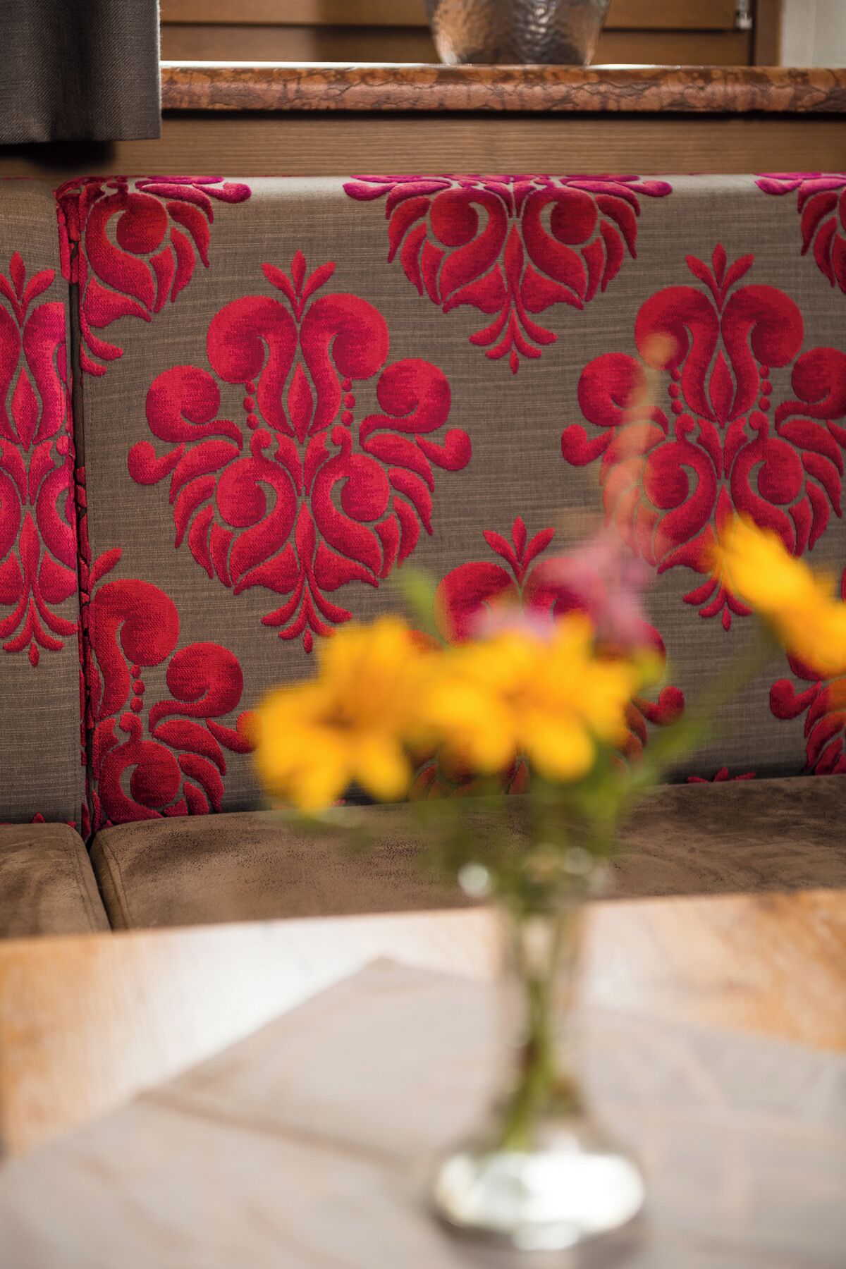 A sofa with a patterned fabric and a vase with flowers on a table.