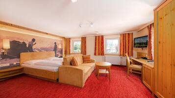 A hotel room with a bed, a sofa, a desk, and a TV.
