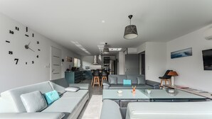 A modern living room with a sofa, coffee table, and a wall clock. - Holiday Home in the Heart of the Basin with Pool (Cazaux)