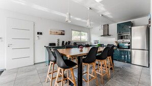 A modern kitchen with a central island, black chairs, and stainless steel appliances. - Holiday Home in the Heart of the Basin with Pool (Cazaux)