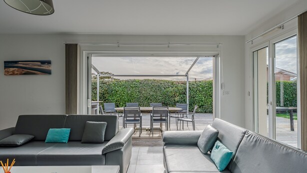 A modern living room with a sofa, coffee table, and a dining area with chairs and a table. - Holiday Home in the Heart of the Basin with Pool (Cazaux)