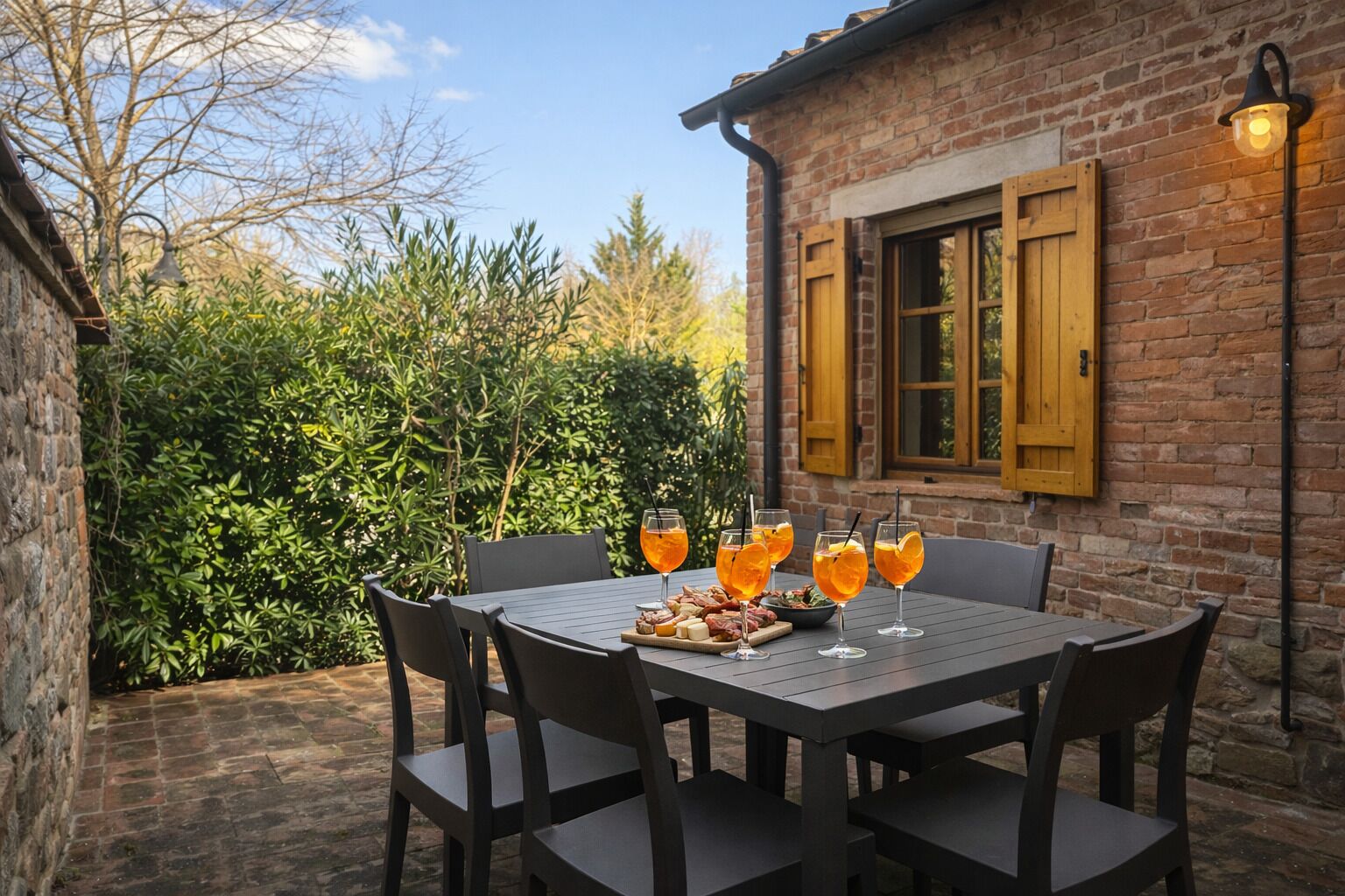 A brick building with a wooden window shutter, a table with chairs, and a glass of orange juice.